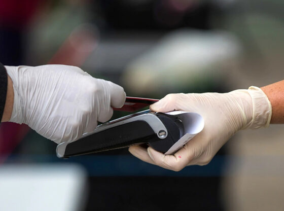 gloved hands making a payment using a chip reader